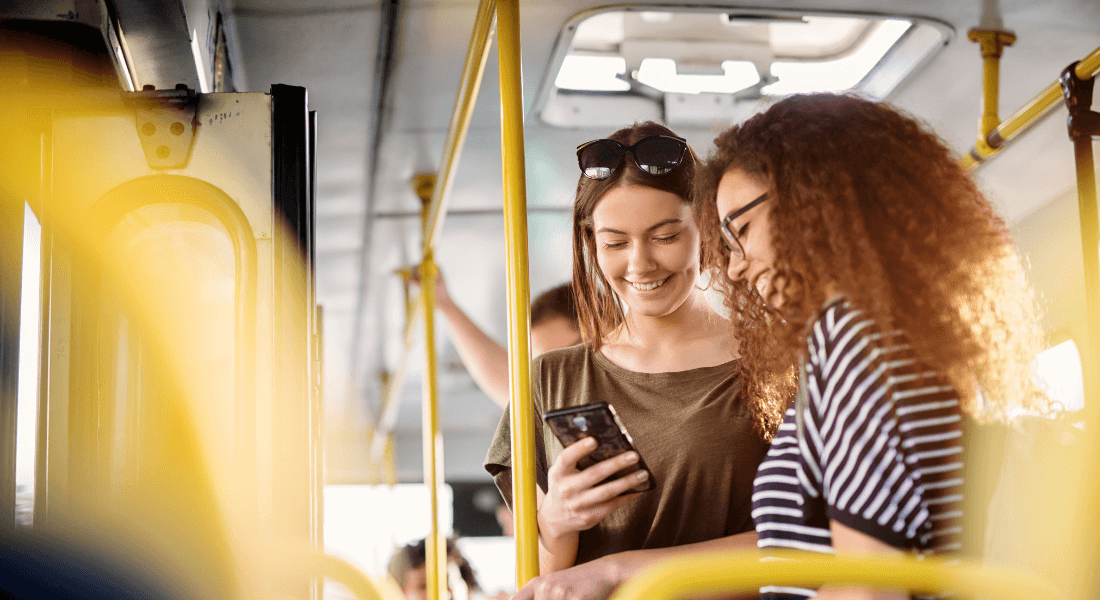 two women using smartphone in public transportation