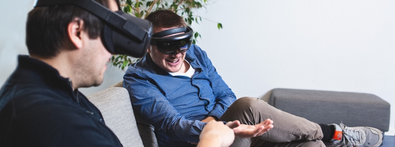 Two persons with VR headsets stretching out their hands