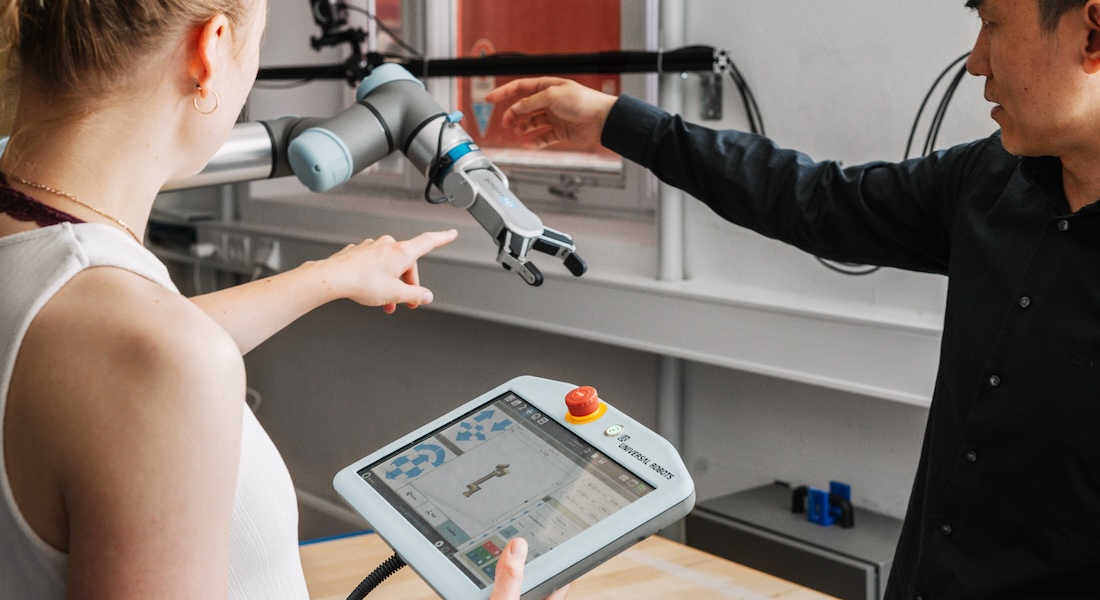 Woman and man experimenting with robot arm
