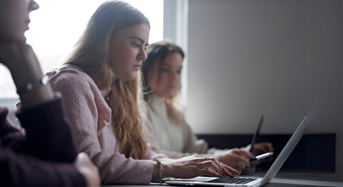 Tre personer arbejder koncentreret foran bærbare computere